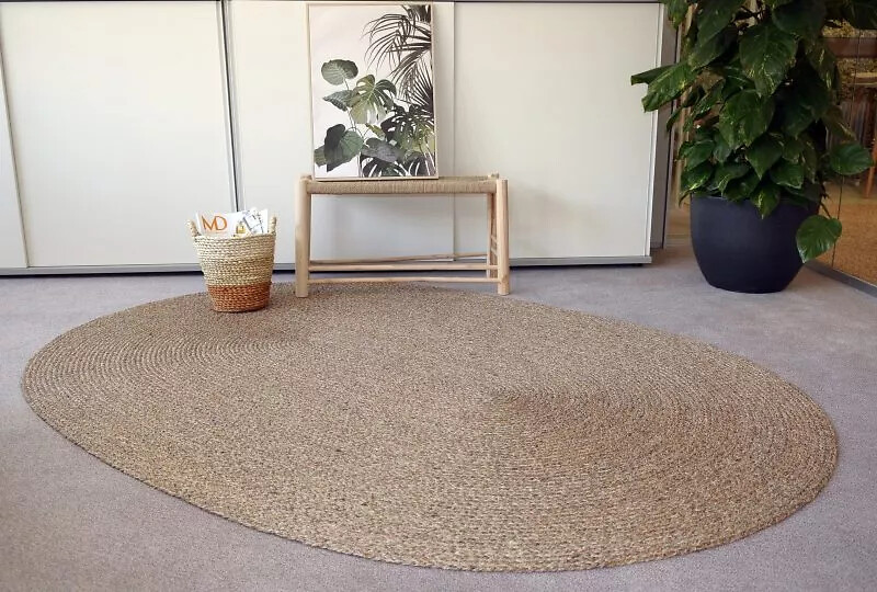 Ovaler Sisalteppich in Naturfarbe auf Teppichboden neben Korb und Bank