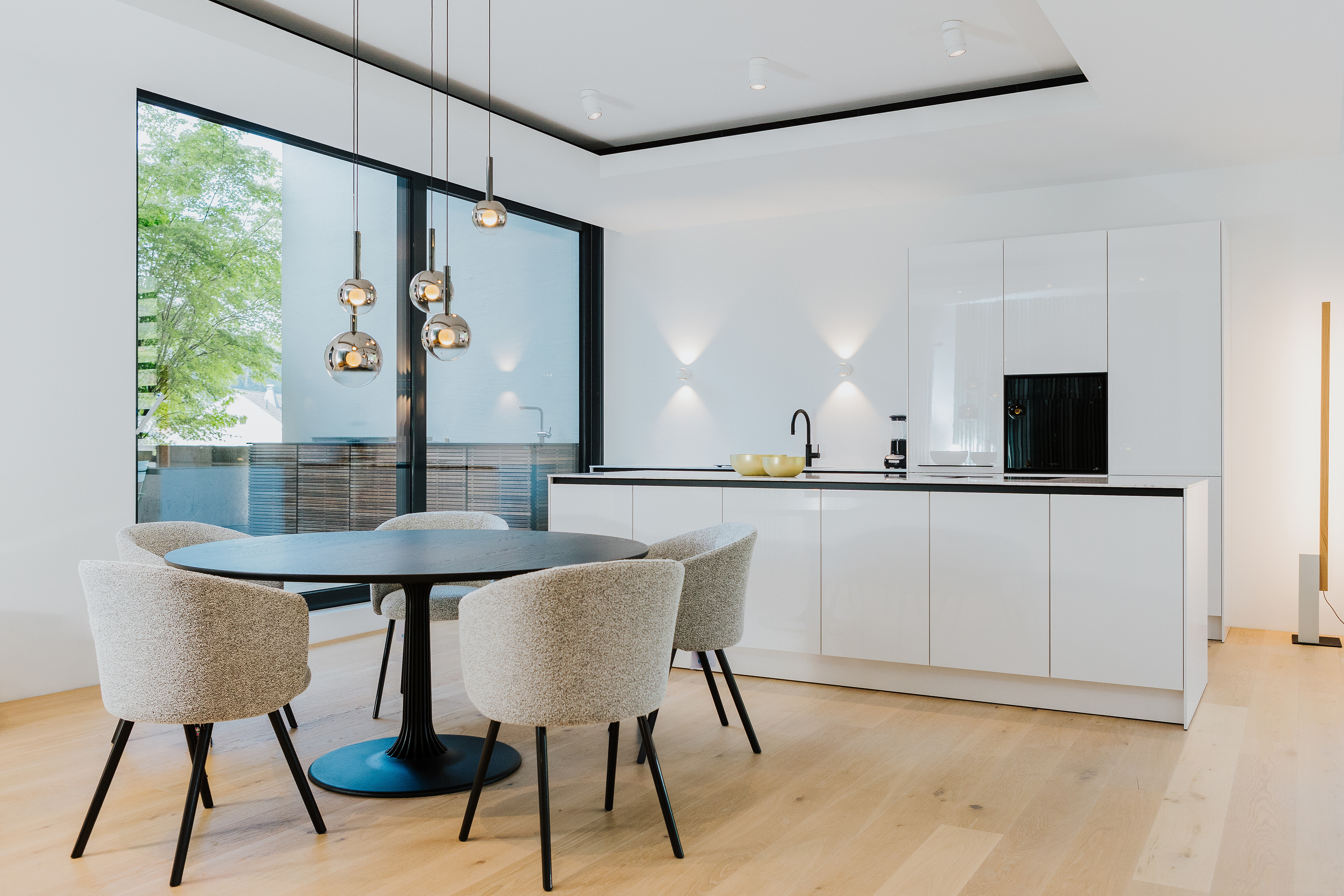 Moderne Wohnküche in weißer und schwarzem rundem Esstisch mit Polsterstühlen 