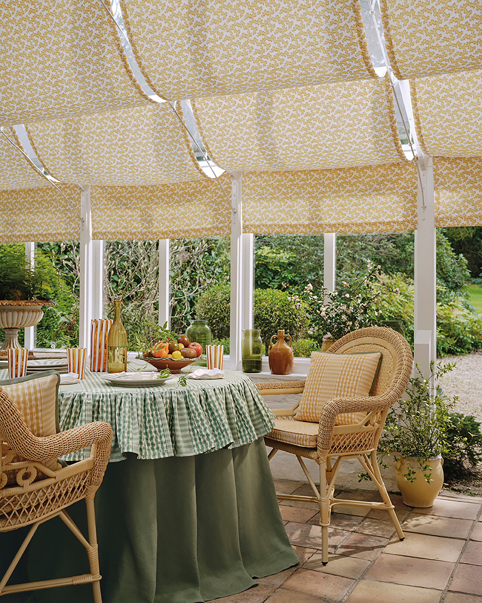 Textilbespannte Pergola mit gedecktem Tisch und Rattanstühlen im Garten  