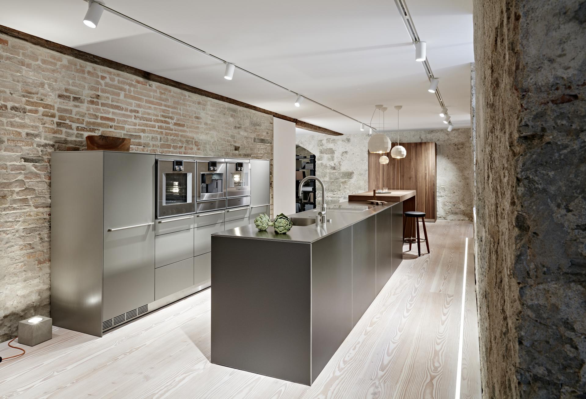 Bulthaup Küche mit Kochinsel und Backsteinwand in puristisch-modernem Ambiente