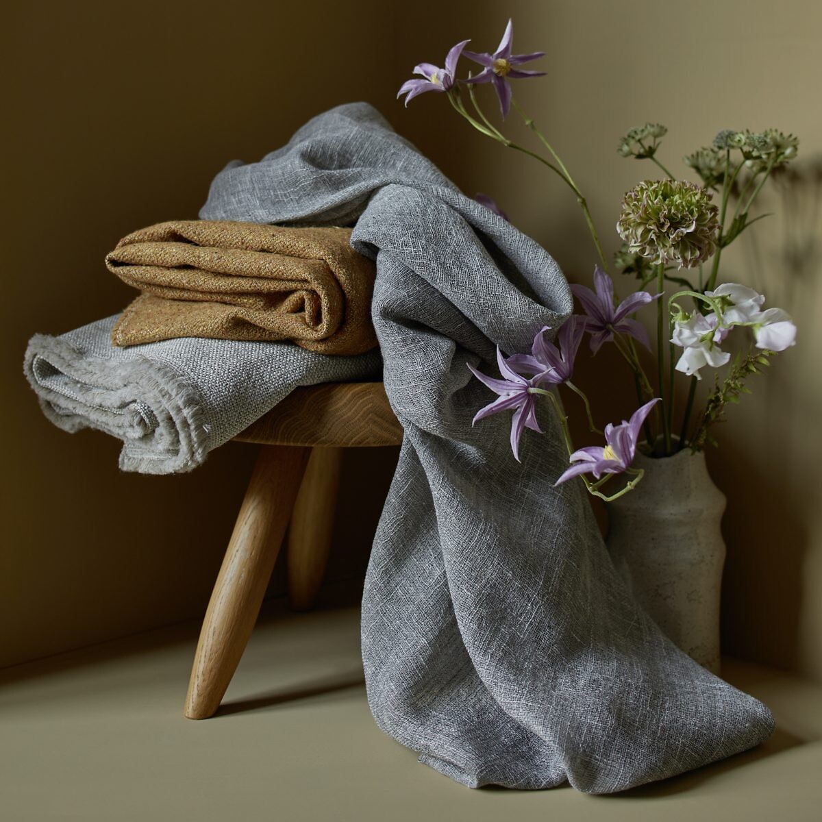 Leinentücher in Naturtönen locker auf Hocker und Boden drapiert