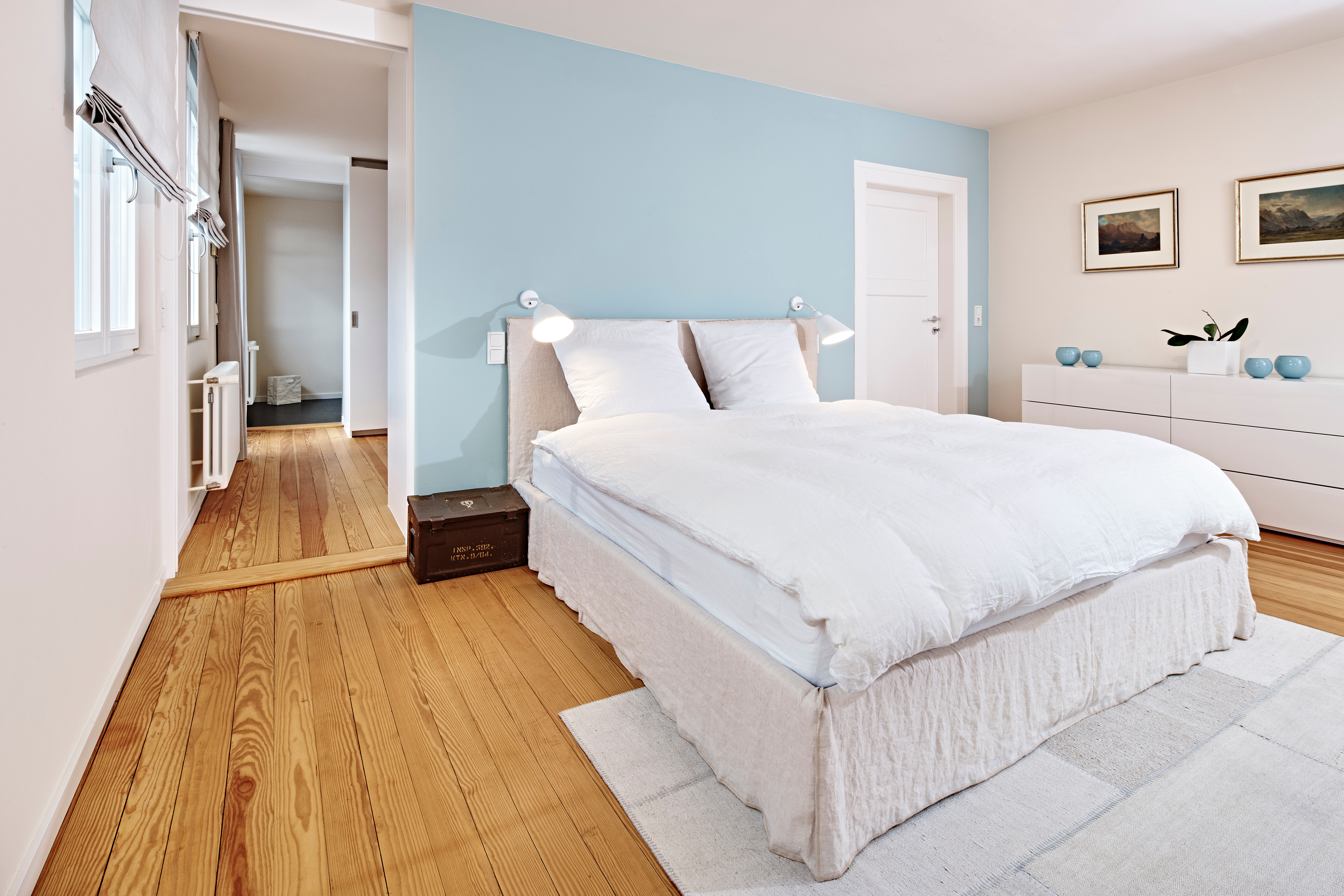 Die ice-blaue Wand, die warmen Textilien und der alte Holzdielenboden bieten dem Bett Ghost von Gervasoni einen stimmungsvollen Rahmen.