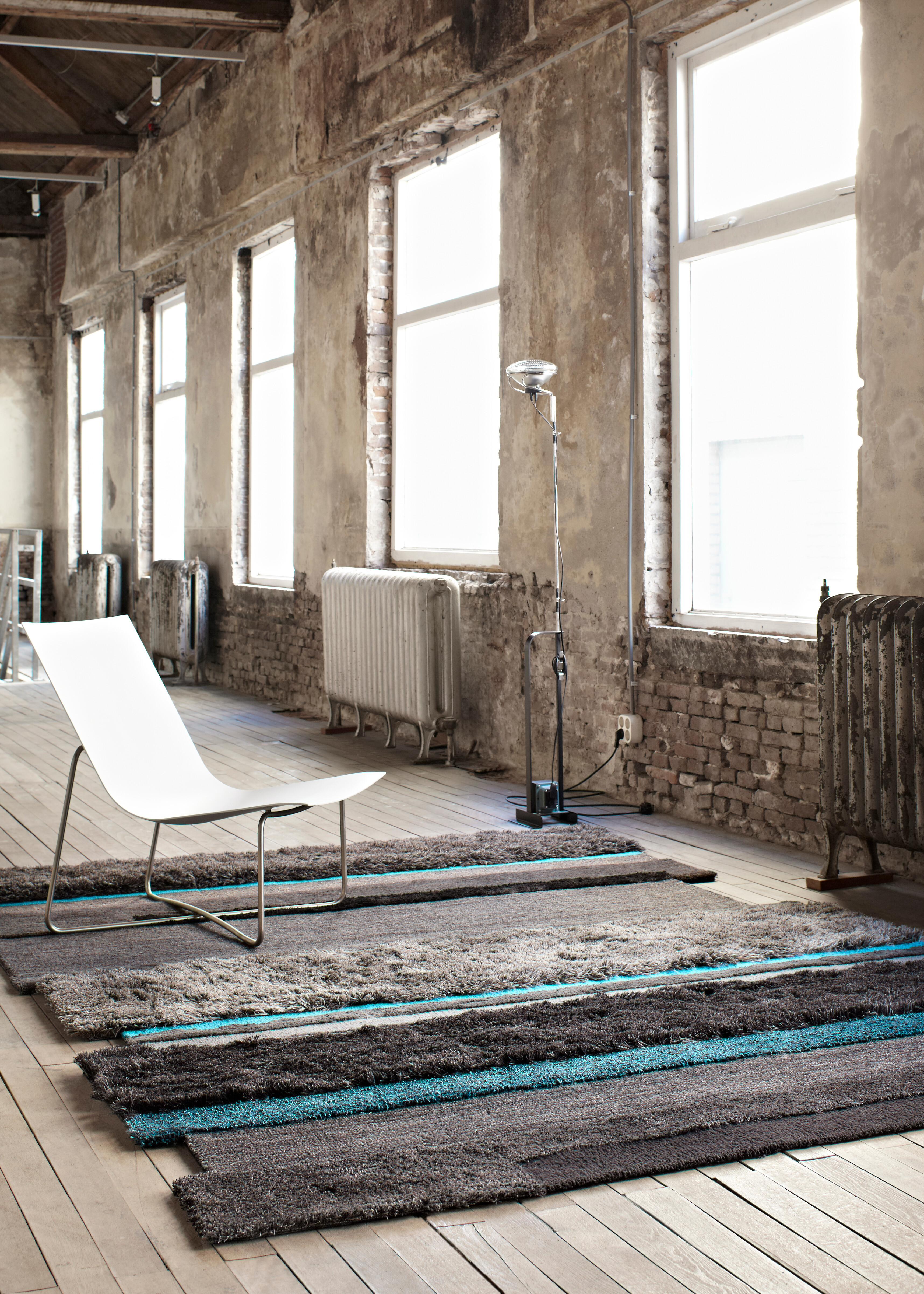 Wohnraum mit Designteppich in grau und türkis auf hellem Dielenboden