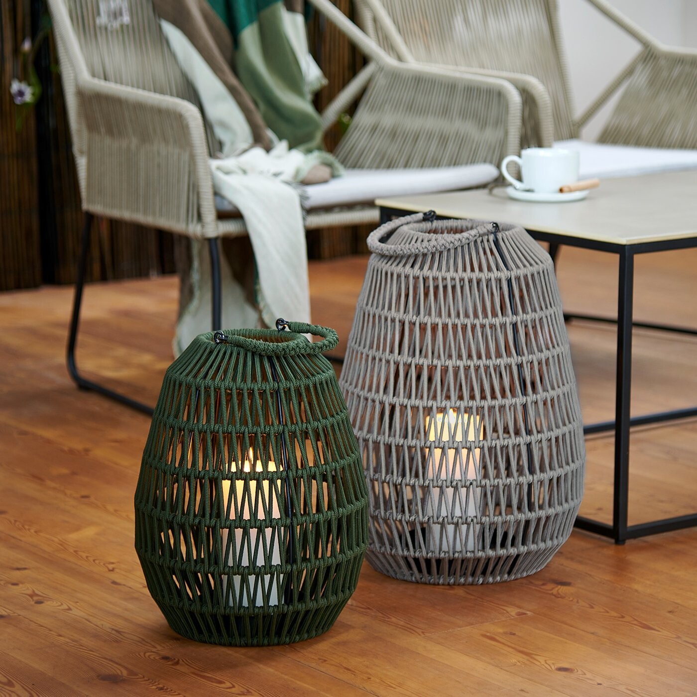 Zwei große Flechtlaternen mit Licht, platziert auf geöltem Holzboden