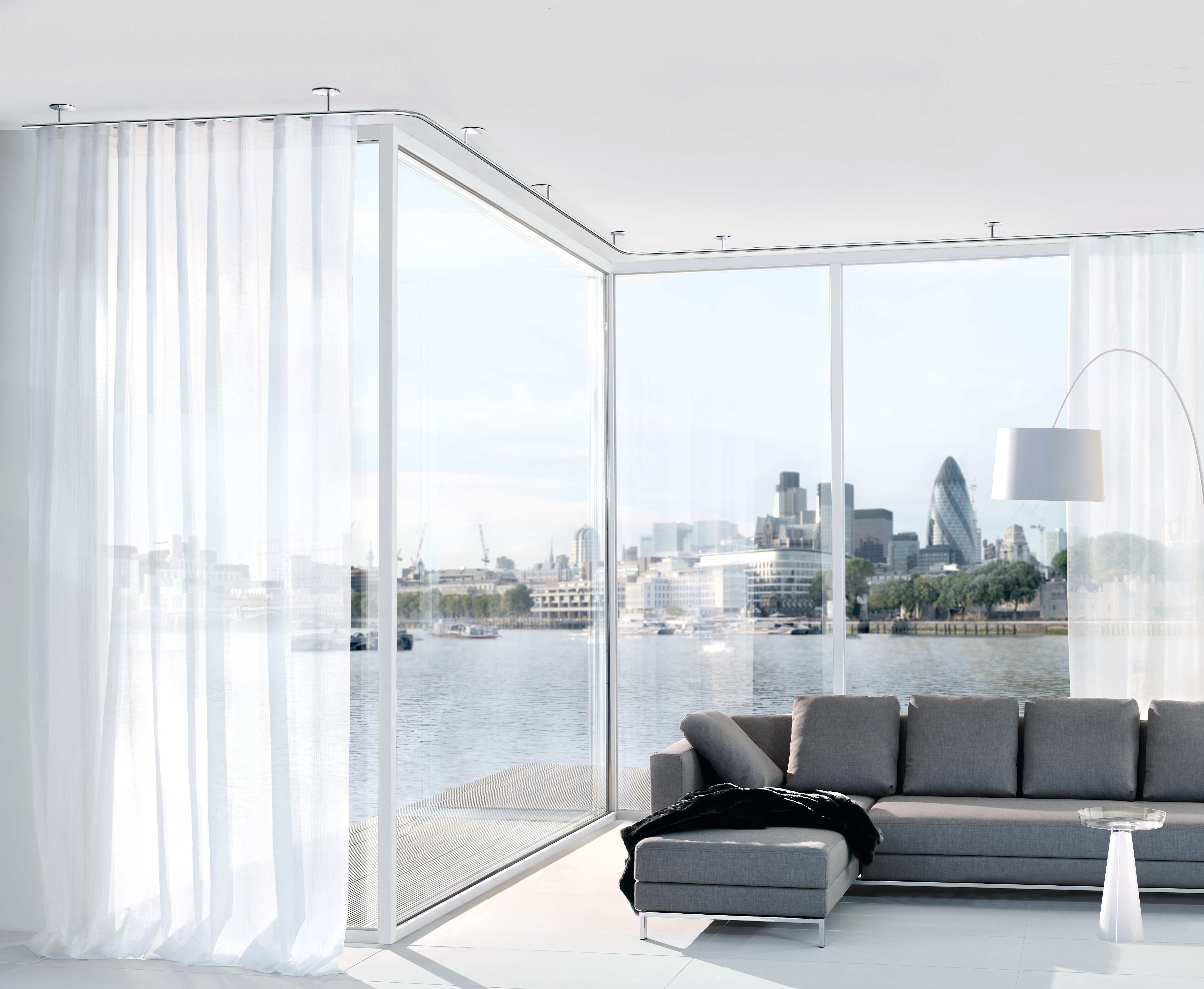 Weißer Vorhang an Deckenlaufschiene vor Panoramafenster mit Blick auf Skyline
