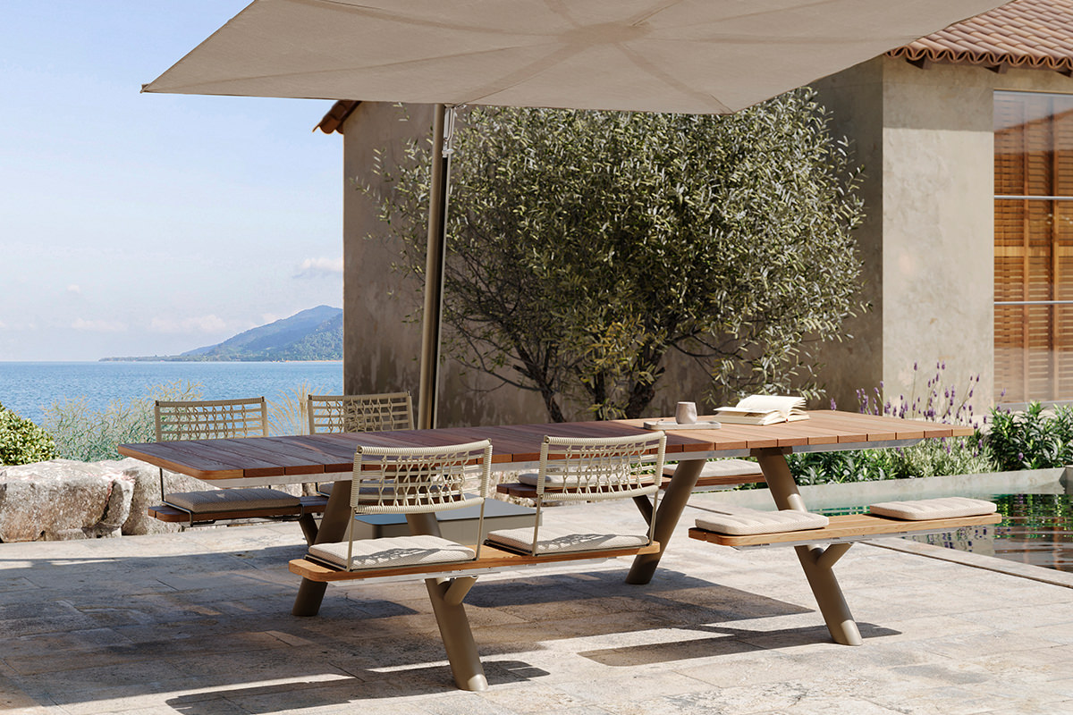 Extremis Panigiri Bank-Tisch-Kombination: stilvolle, funktionale Sitzgelegenheit im Freien. Der große Sensu Sonnenschirm sorgt für angenehmen Schatten. Ideal für entspannte Stunden am Meer mit Bergblick.