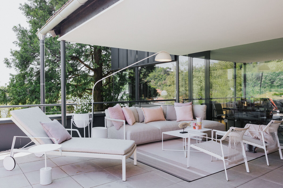 Lounge-Ensemble auf der Dachterrasse Tiengen mit Sonnenliege, Sofa und zarten roséfarbenen Akzenten  