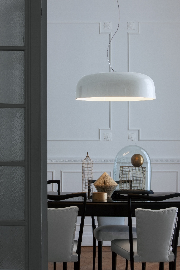 Pendelleuchte Canopy von Oluce über dunklem Esstisch mit Polsterstühlen im Raum