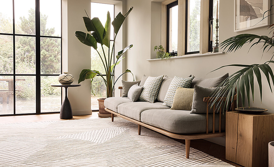 Teppich mit dezentem Linienmuster in hellem Beige in modernem Wohnraum mit Pflanzen  