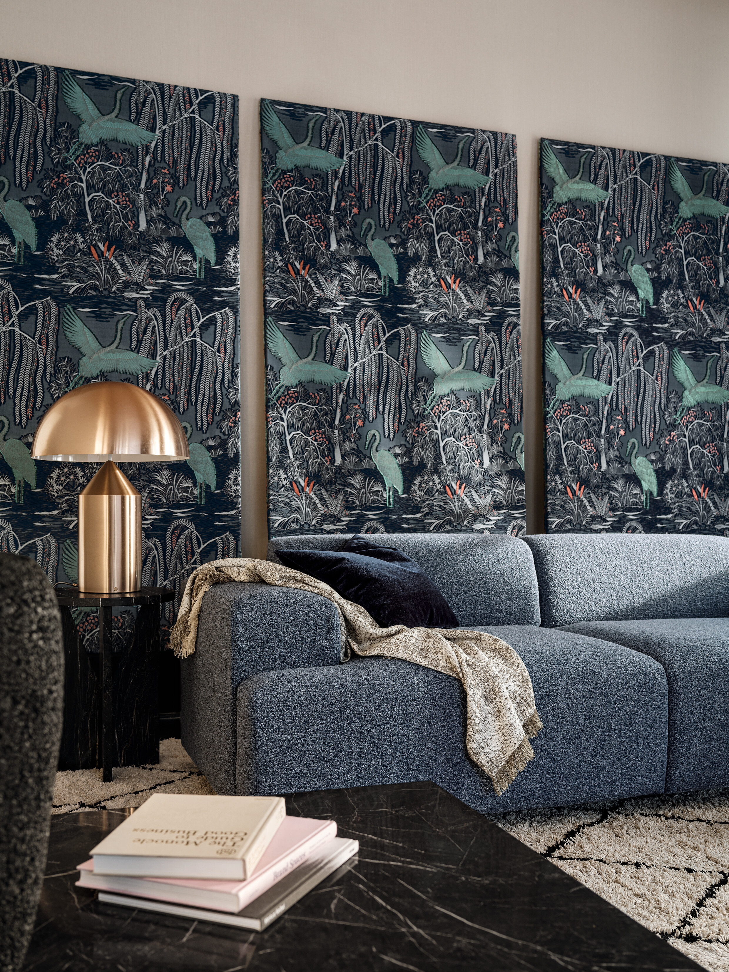 Dunkelblaue Couch vor dreiteiligem Wandbehang mit Dschungelmotiv