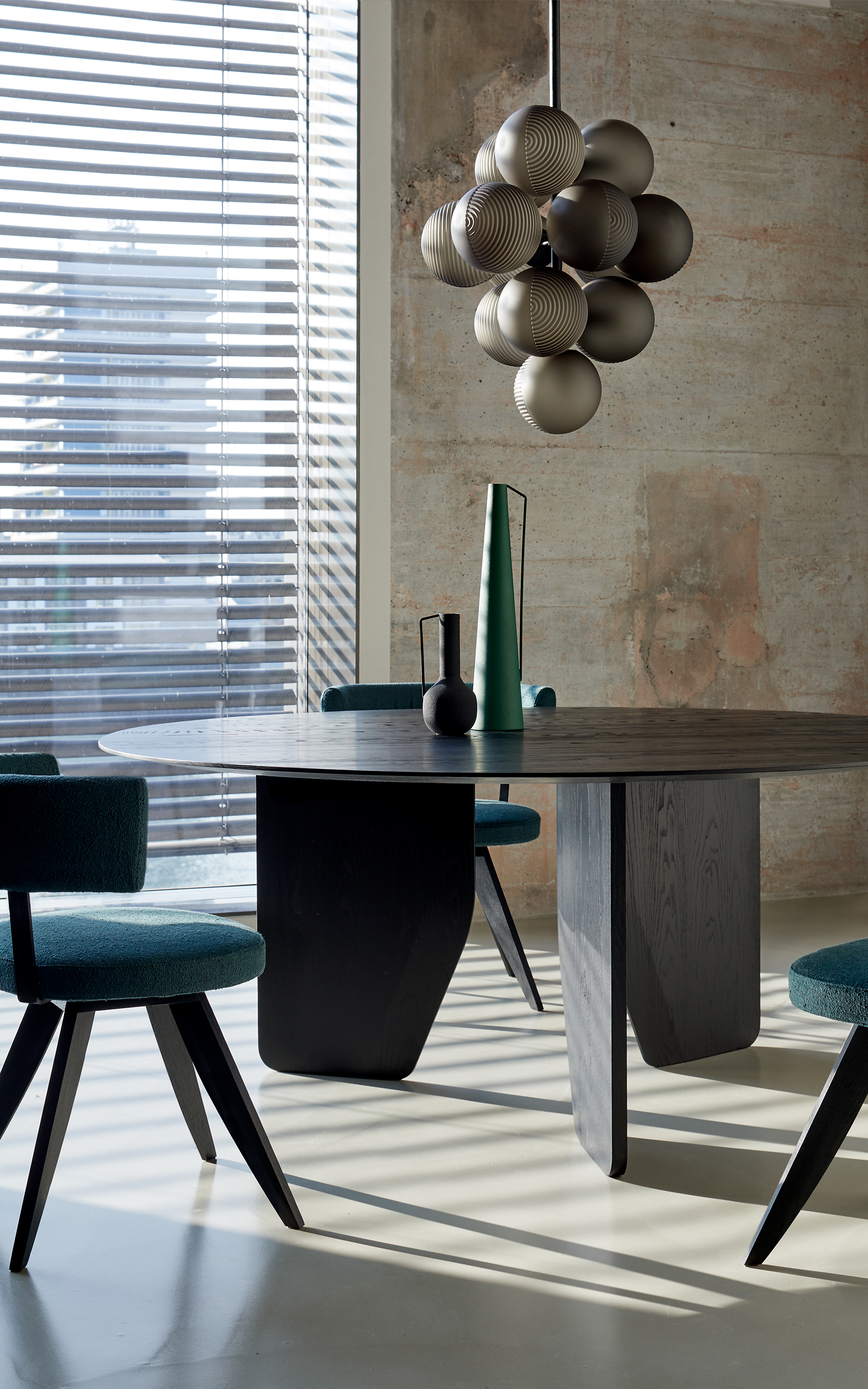 Runder Esstisch mit dunkler Holzplatte und vier samtbezogenen Stühlen in tiefem Blau  