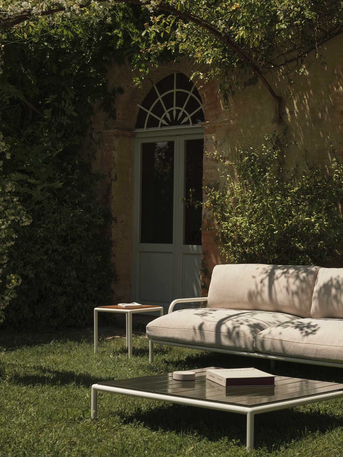 Fast Sofa Roè in hellem Stoff auf einer Rasenfläche vor einer historischen Hausfassade