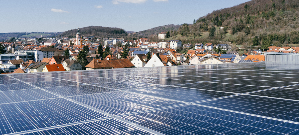Photovoltaikanlage auf dem Dach von Seipp Wohnen in Tiengen, im Hintergrund Stadtansicht und bewaldete Hügel des südlichen Schwarzwalds.