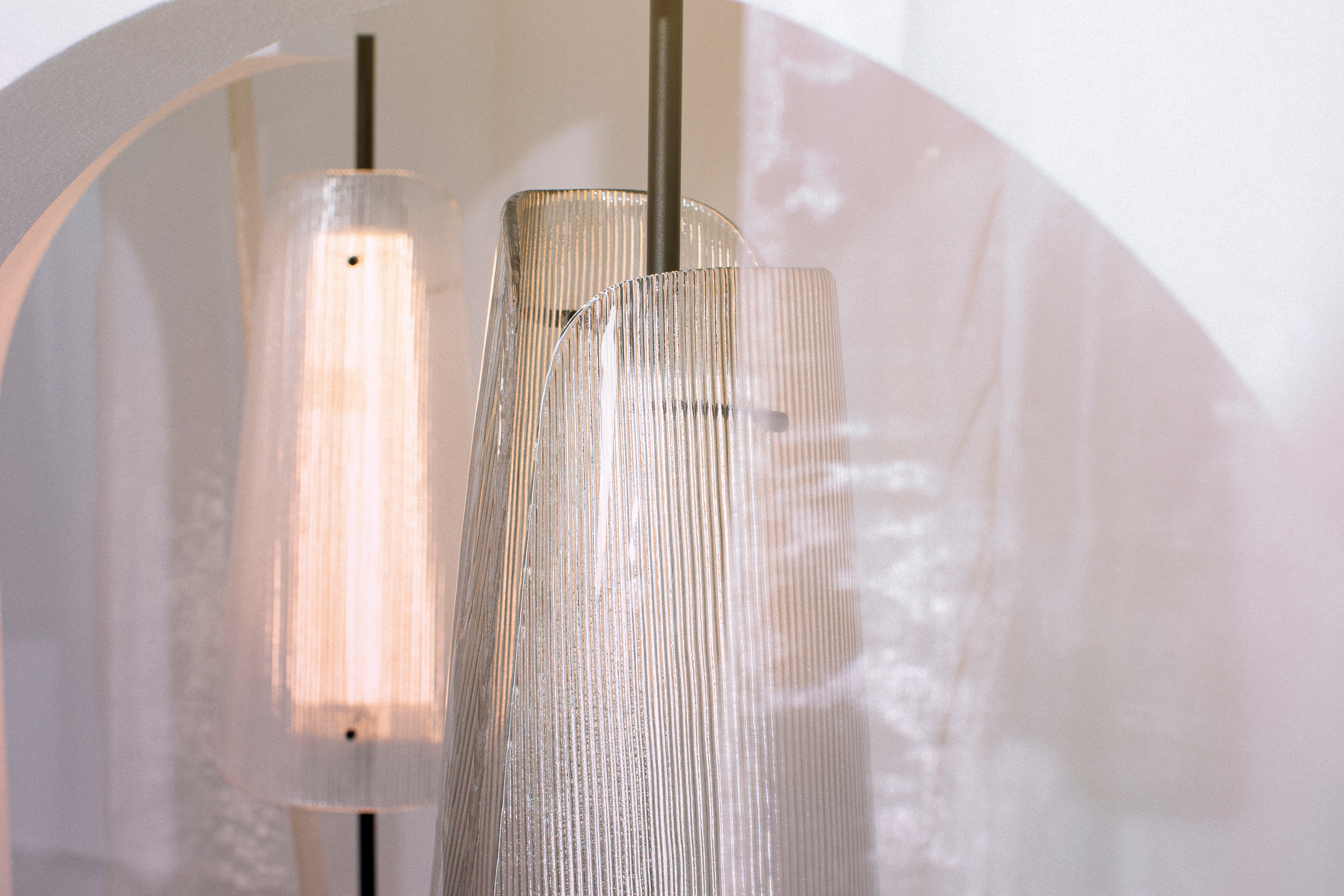 Zwei transluzente Leuchten mit gerilltem Glas vor weißem Hintergrund mit Lichtreflexen  