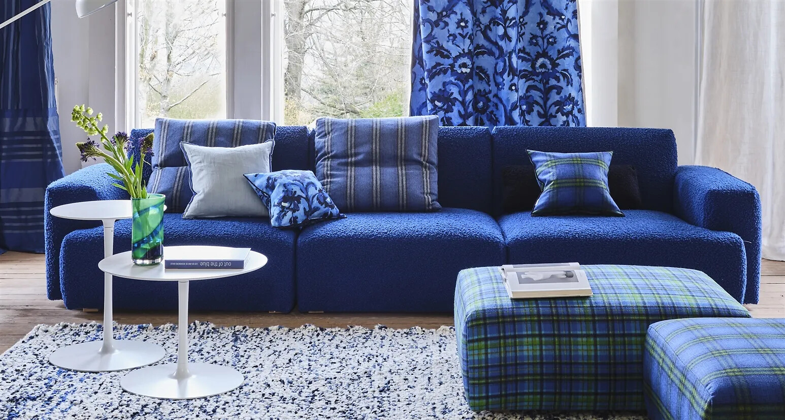 Blaues Sofa mit strukturierter Oberfläche, kombiniert mit verschiedenen blau gemusterten Kissen  