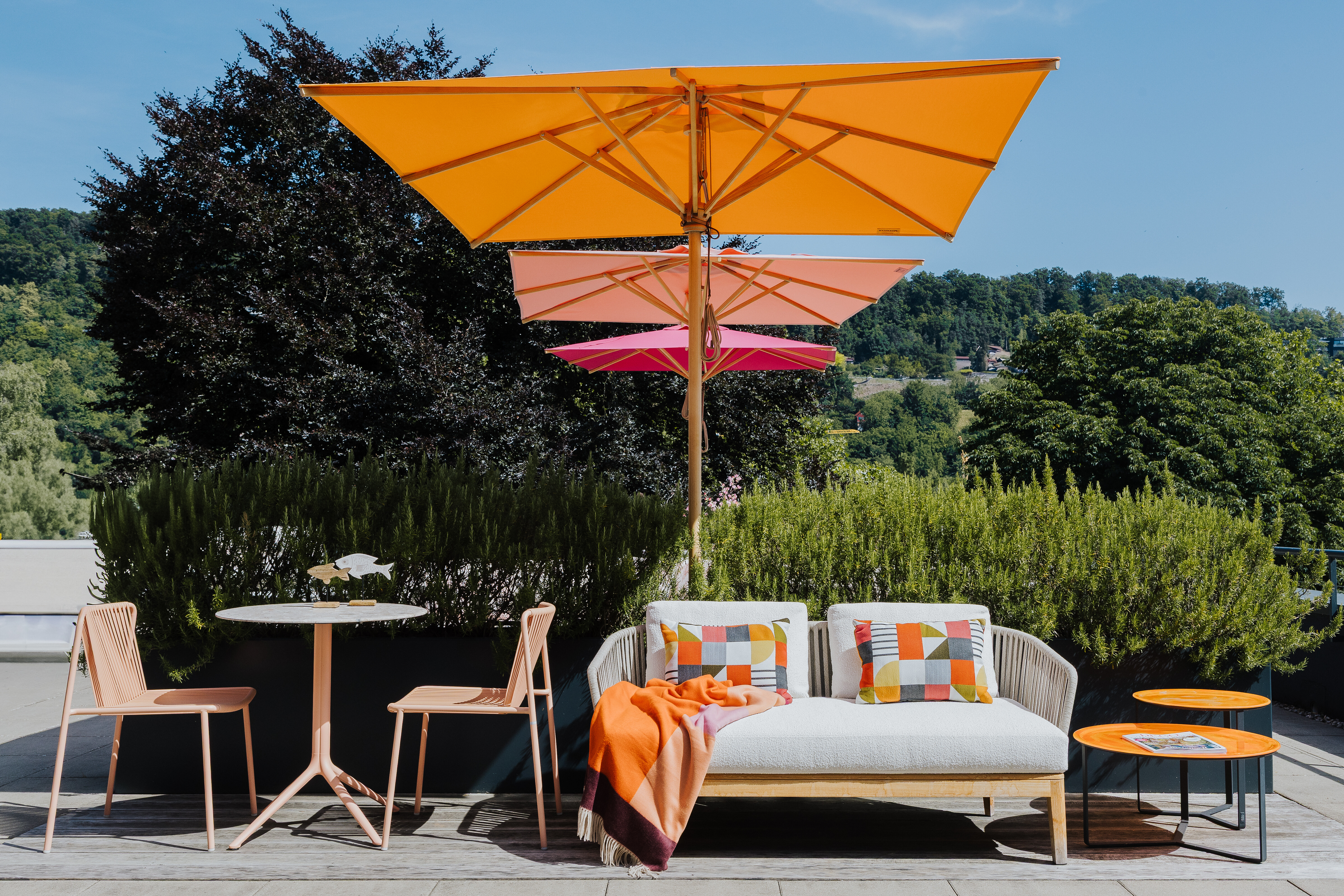 Terrasse in Tiengen mit Gartenmöbeln in warmen Farben, ergänzt durch orangefarbene Sonnenschirme.  
