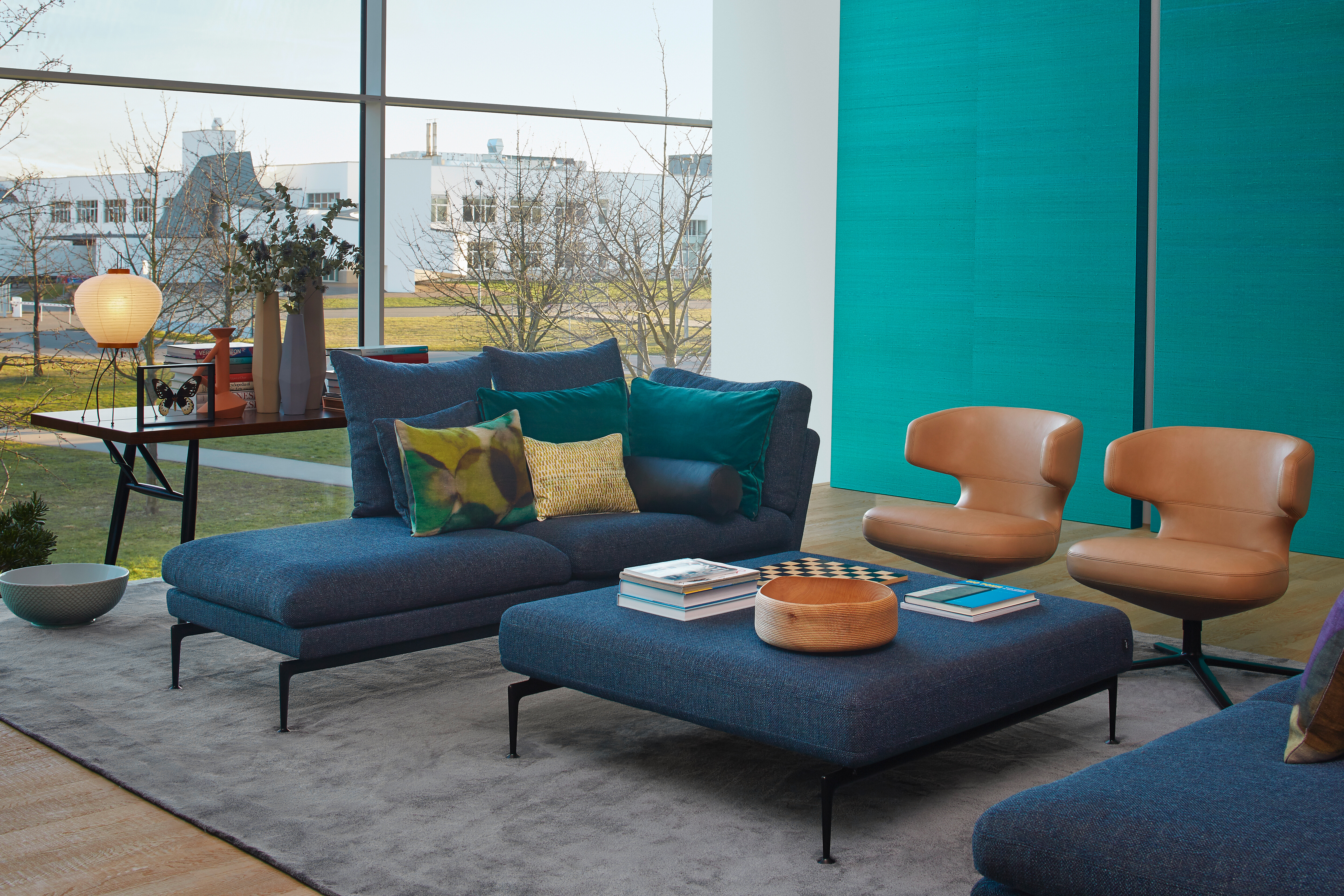 Vitra-Sitzgruppe mit blauen Polstermodulen, beigen Sesseln und Couchtisch vor bodentiefem Fenster
