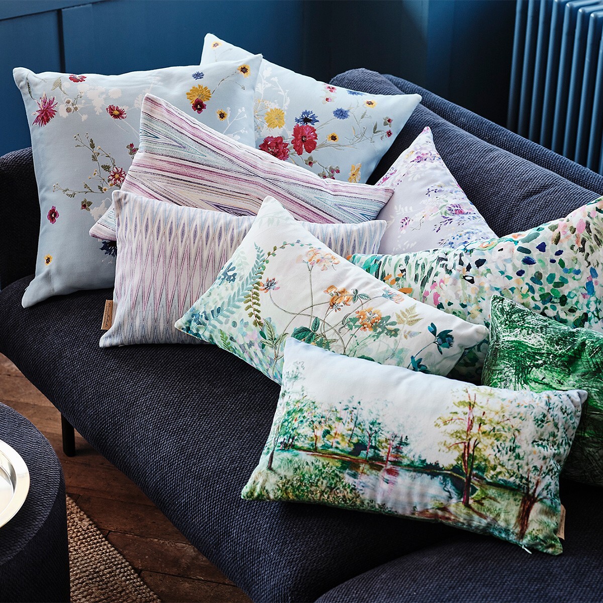 Sofa mit neun gemusterten Kissen in floralen und grafischen Designs