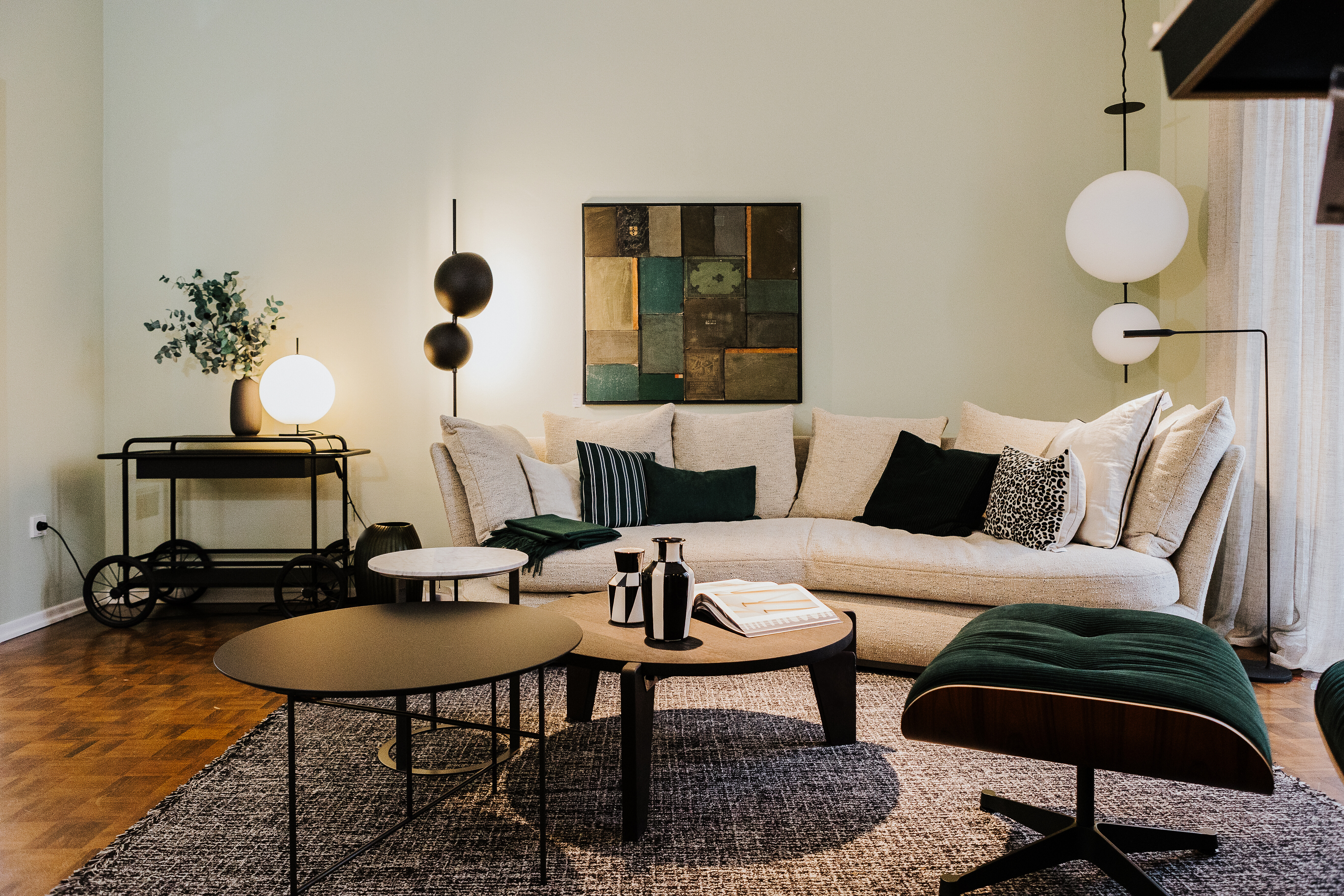 Wohnbereich mit hellem Sofa, runden Beistelltischen und Stehleuchten auf Teppich in gedeckten Tönen