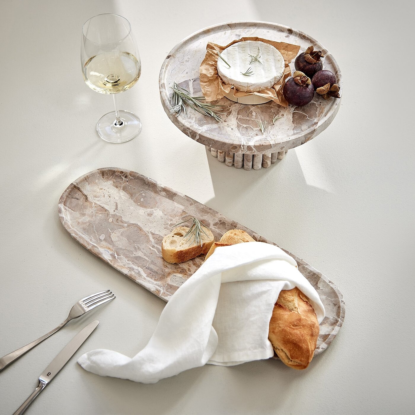 Servierschalen aus Naturstein mit Baguette, Camembert und Weißwein gedeckt  