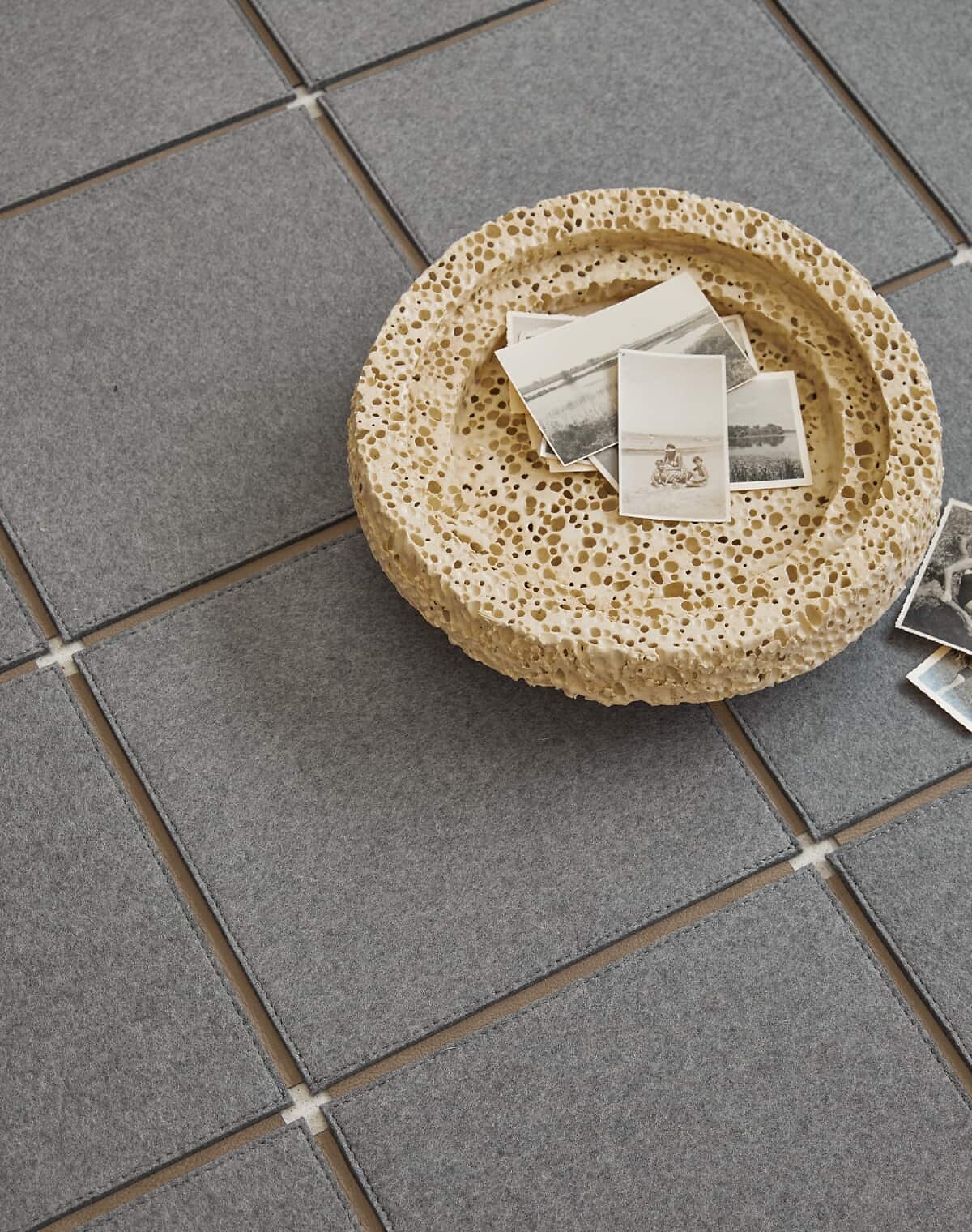 Quadratische Teppichfliesen in warmem Grauton mit strukturierter Steinschale oben