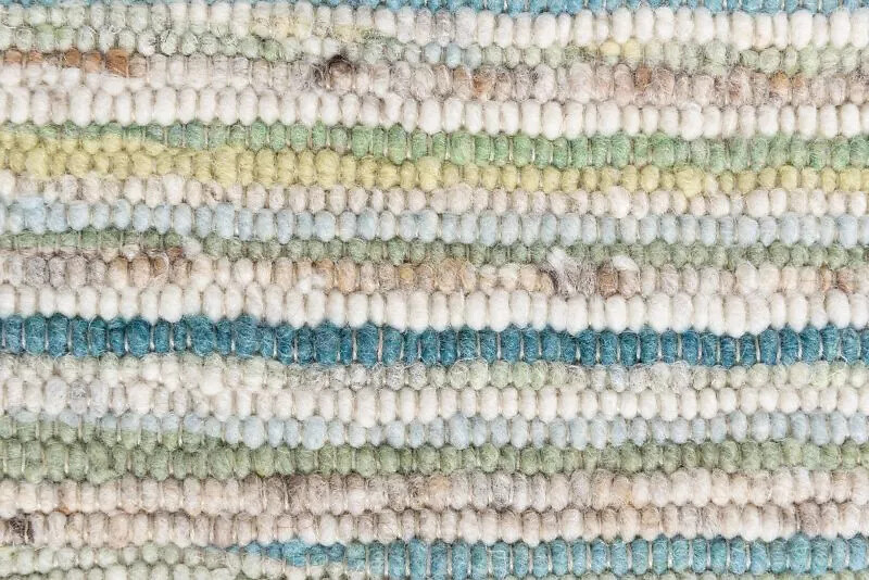 Detailaufnahme eines Wollteppichs mit feiner Streifenstruktur in Naturtönen