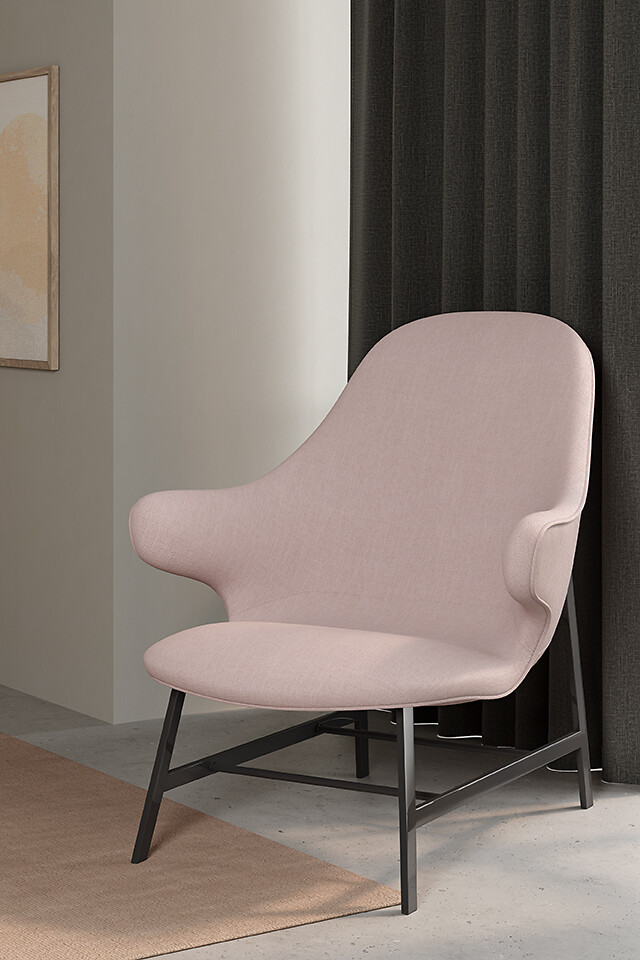 Hellrosafarbener Polstersessel mit schwarzem Gestell vor dunklem Vorhang