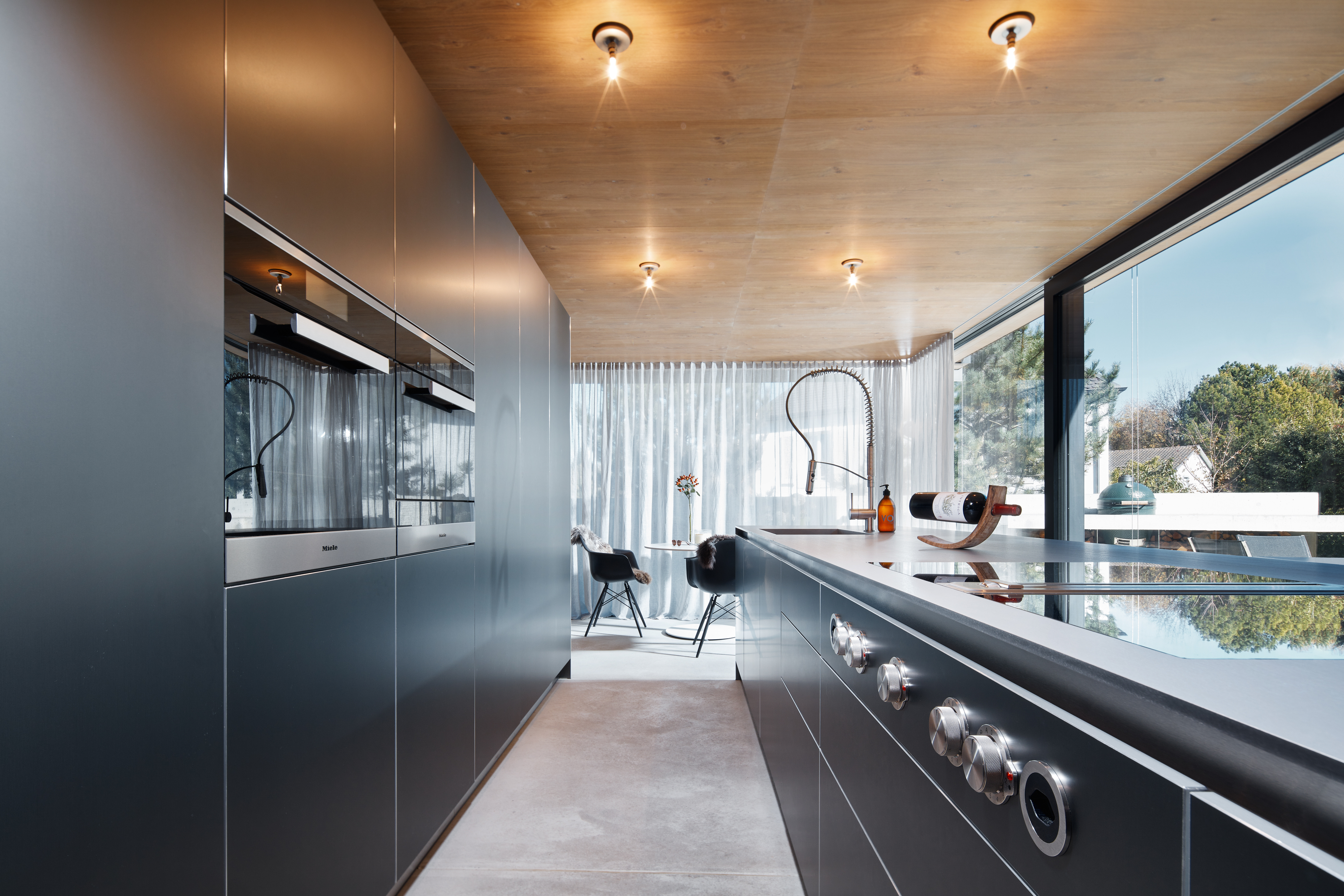 Beton, Holz und Glas bilden die Basis des modernen Neubaus. Mittelpunkt ist das offen gestaltete Erdgeschoss mit Wohn-, Koch- und Essbereich. Eine Besonderheit ist bereits von außen gut ersichtlich – das verbindende Element Eichenholz. Im Erdgeschoss zier