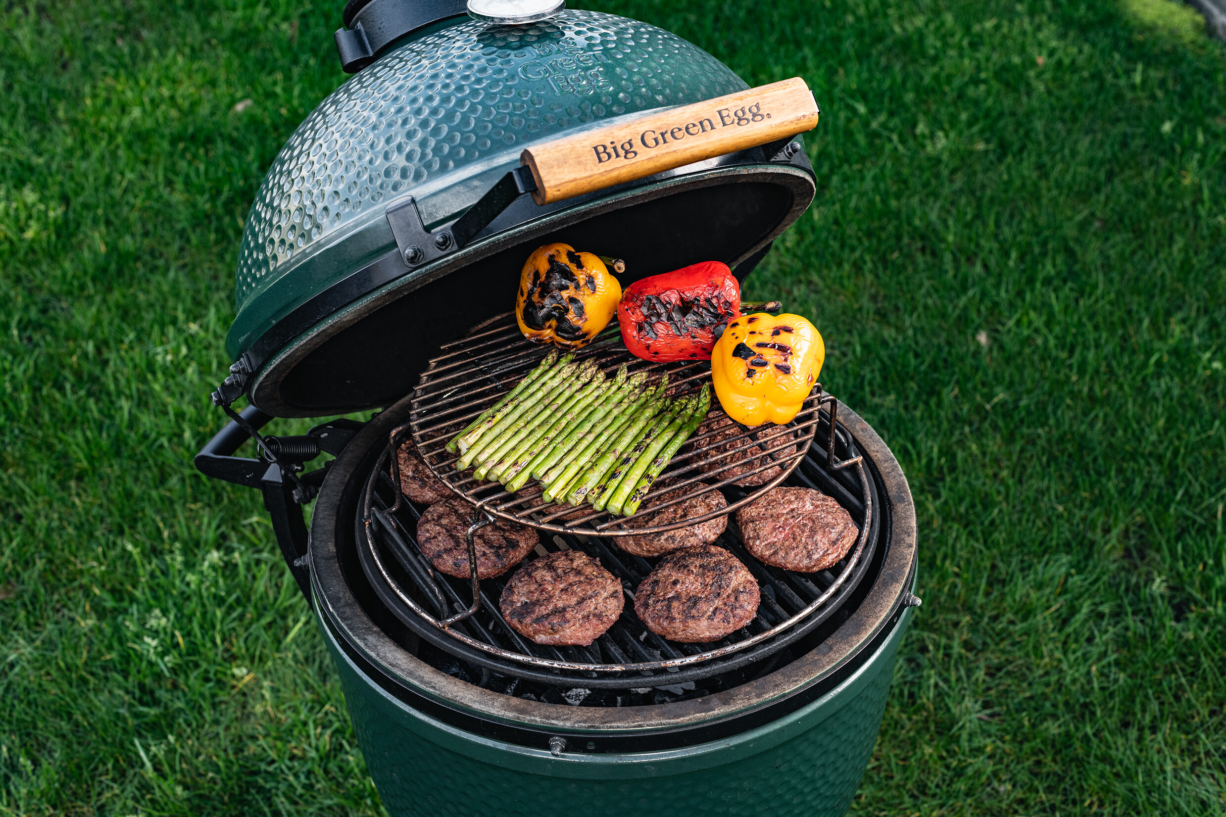 Großer Big Green Egg Grill mit EGGspander, Grillgut auf zwei Ebenen im geöffneten Deckel  