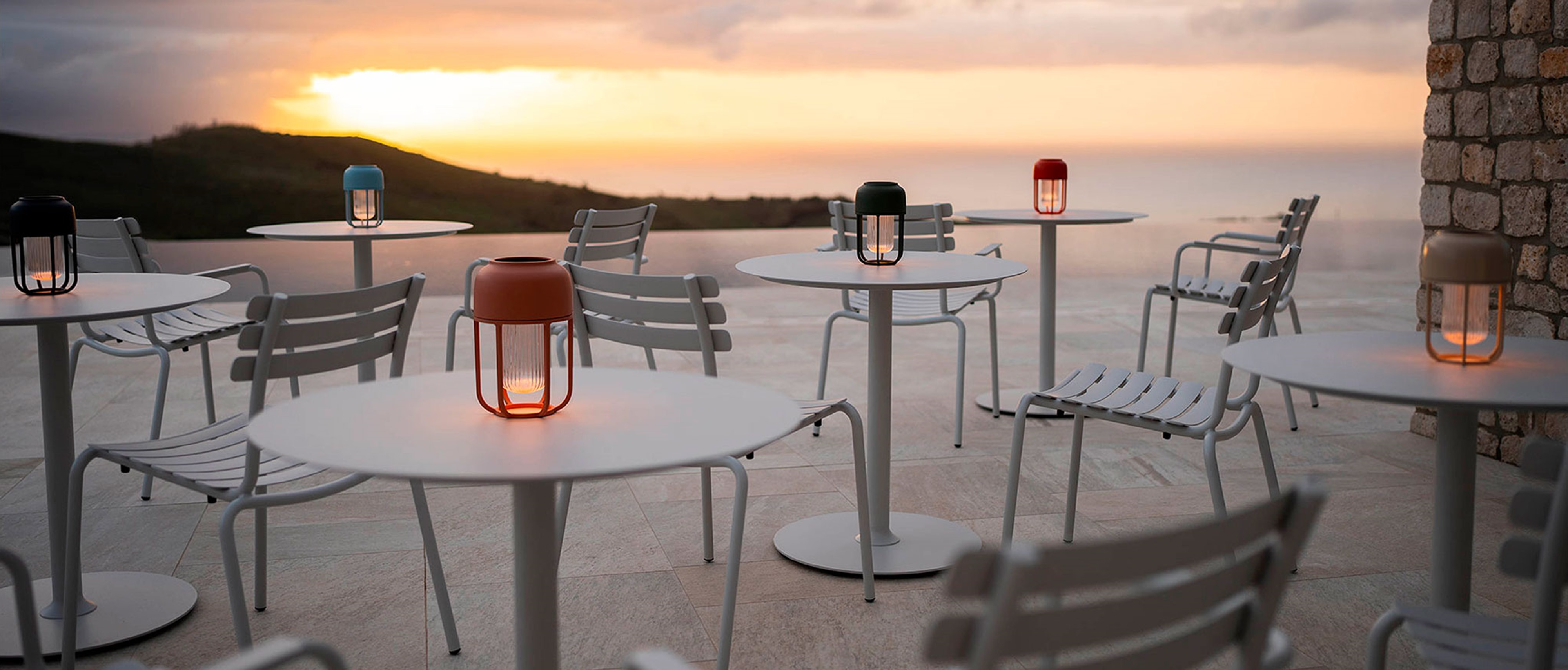 Auf runden Tischen stehen Solarleuchten Light No1 von Houe bei Sonnenuntergang.