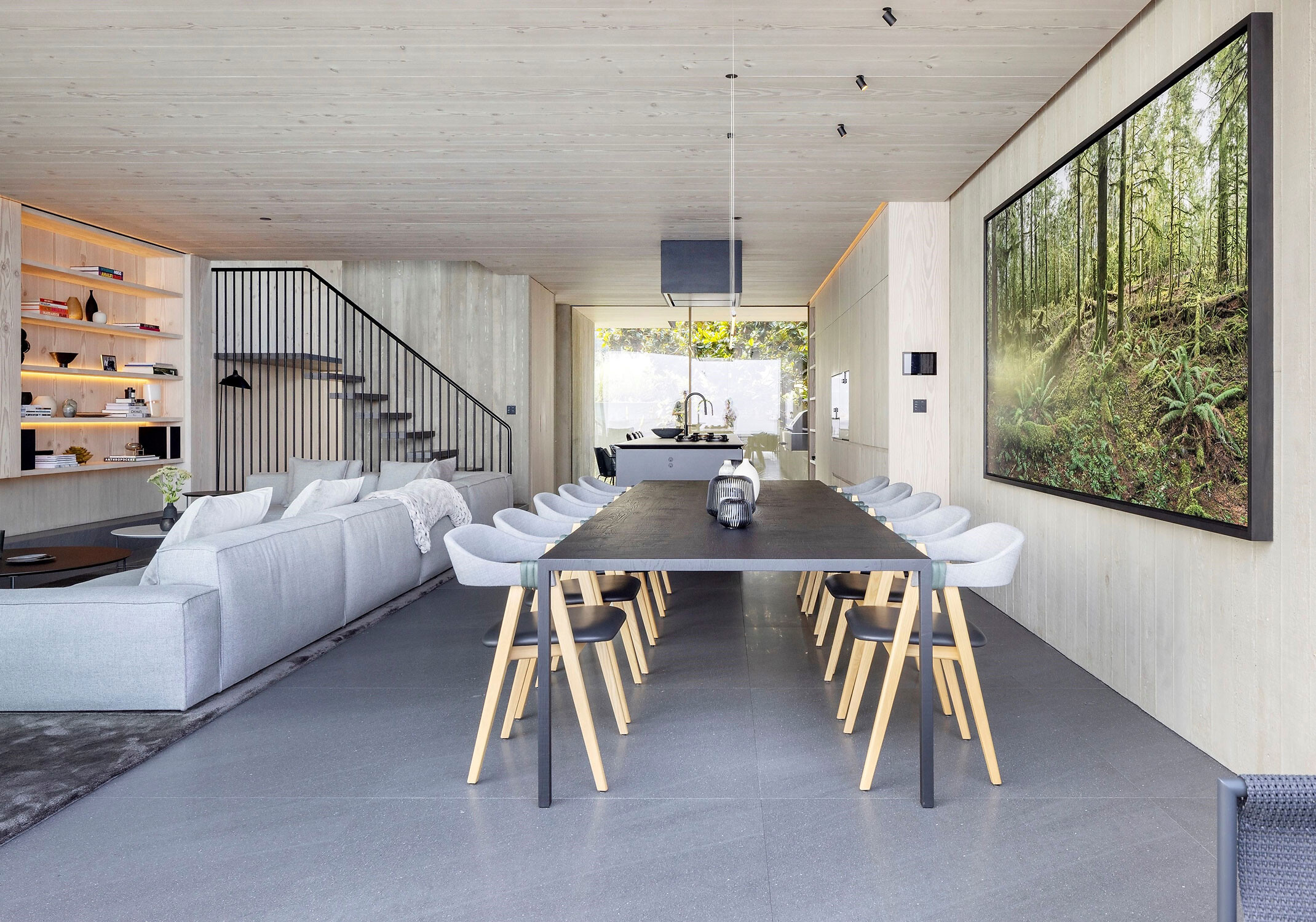 Langer Esstisch mit zehn Stühlen in heller Wohnküche mit großer Glasfront und Kunstwerk