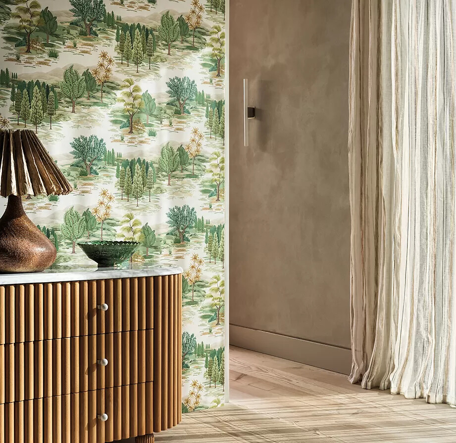 Tapete mit grünen Baumillustrationen hinter Kommode mit Lampe und Glasschale