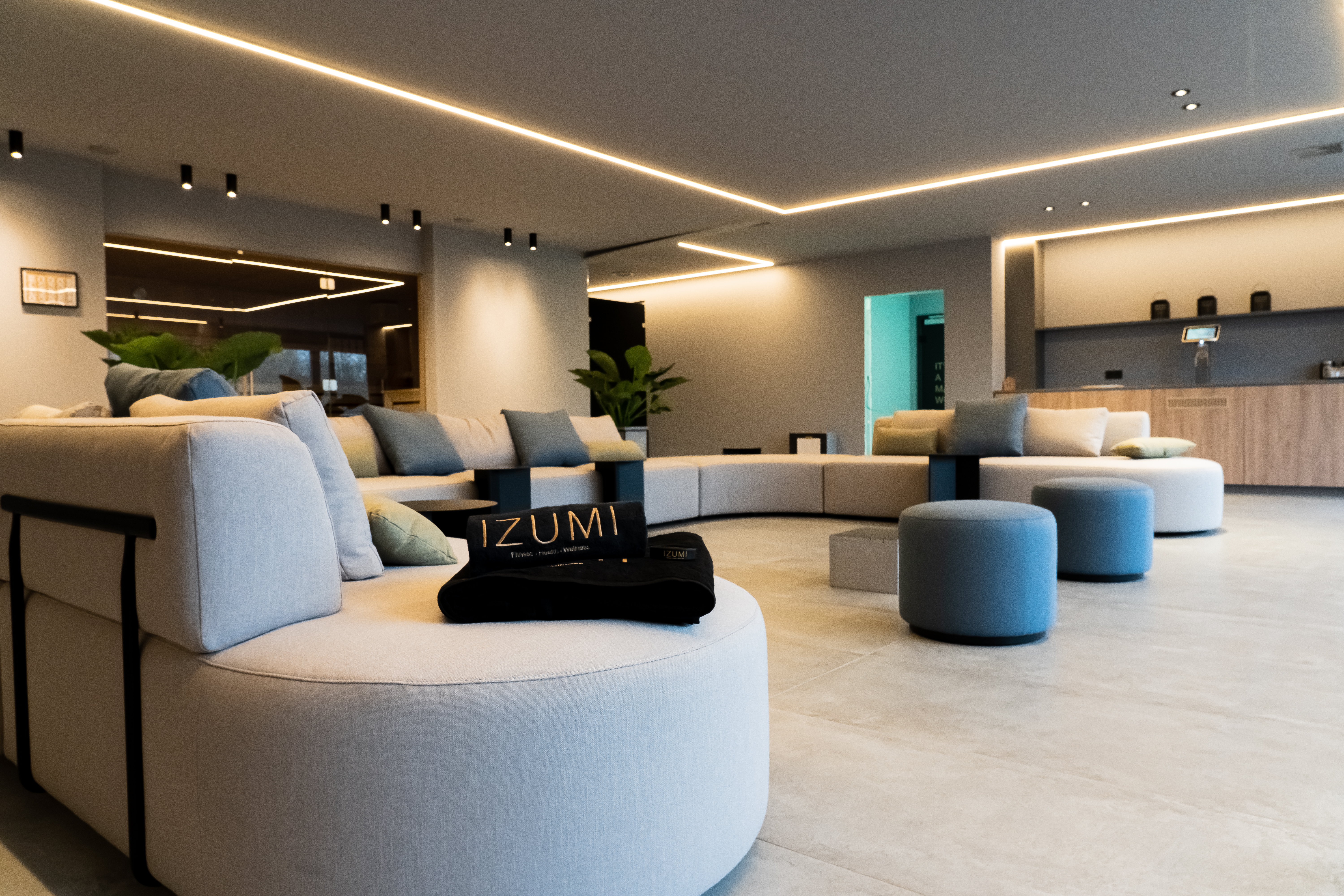 Moderne Lounge mit geschwungener Sofalandschaft, indirekter Beleuchtung und dezenten Blautönen.