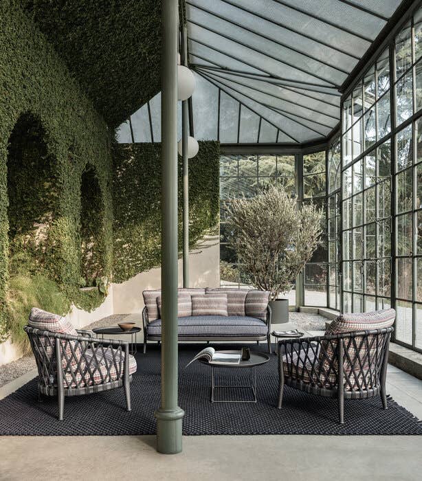 Sitzgruppe mit Sofa und Sesseln Erica von B&B Italia in verglastem Raum mit Rankbewuchs  