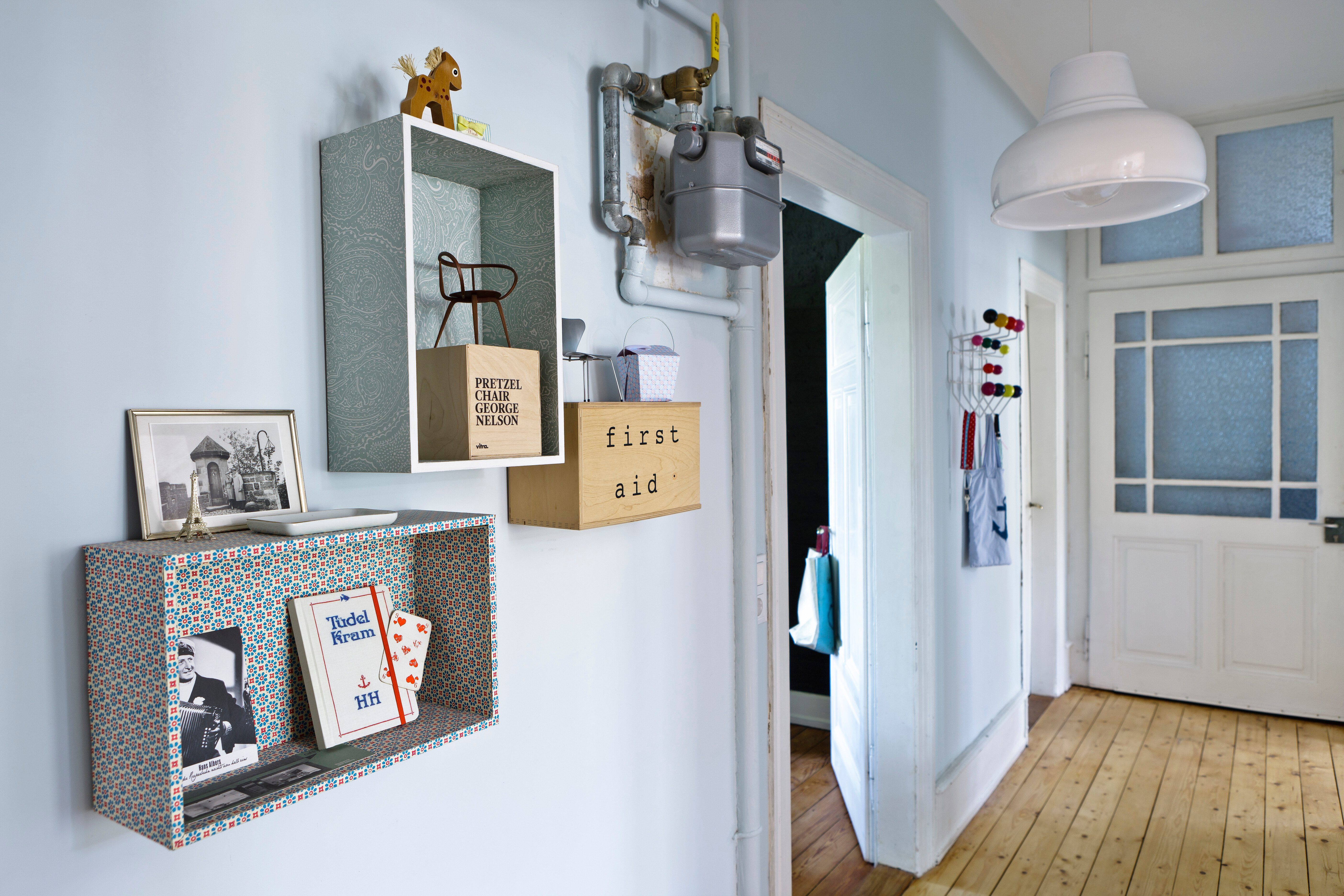Aufbewahrung in kleinen wandhängenden Kisten, Eigenkreation. Im Hintergrund: Klassiker - Wandgarderobe Hang it all von Vitra, Design Charles und Ray Eames.