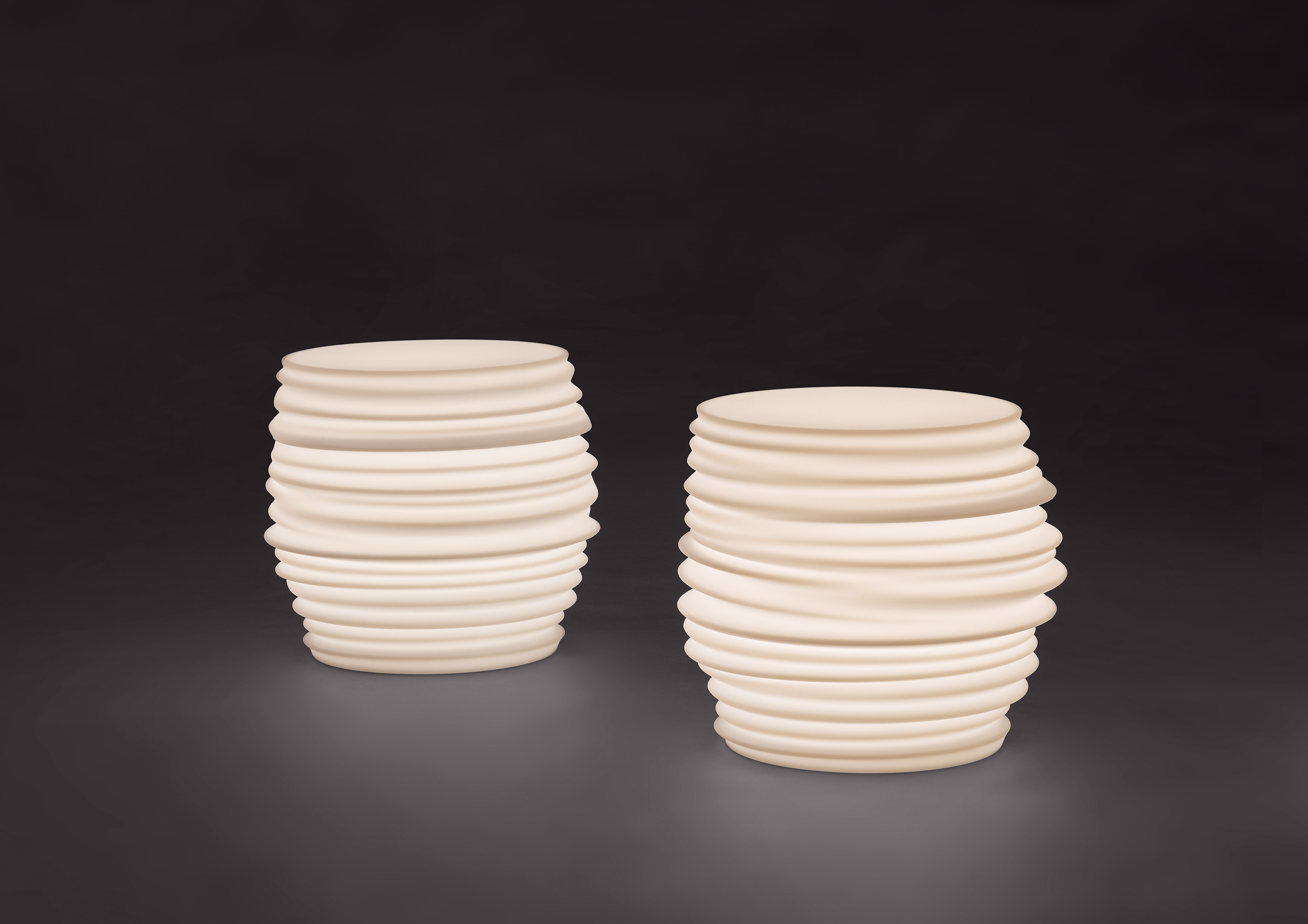 Zwei weiße strukturierte Gefäße vor dunklem Hintergrund mit weicher Lichtführung  