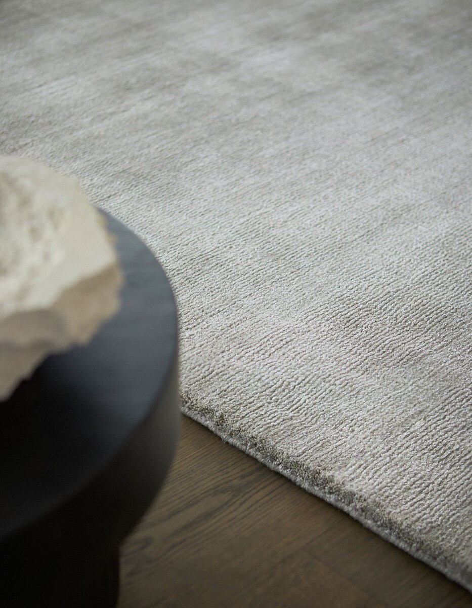 Detailaufnahme heller Teppich neben schwarzem Beistelltisch