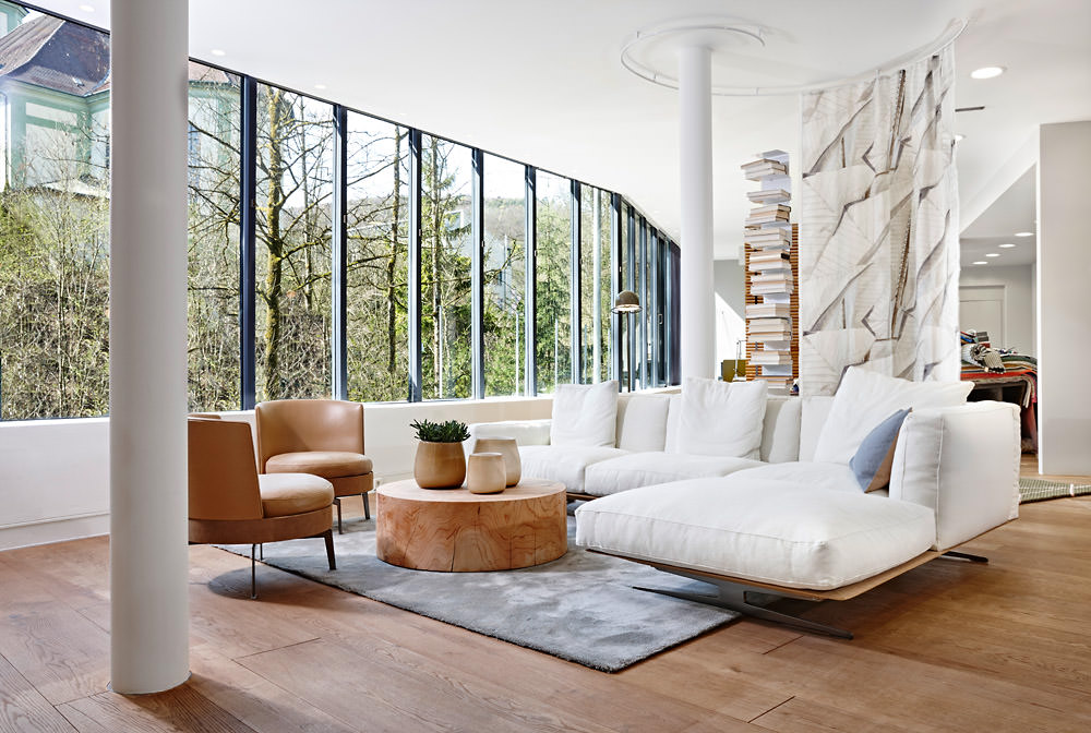 Einblick in die Ausstellung von Seipp Wohnen in Waldshut mit weißem Sofa, Lederstühlen und großem Panoramafenster.