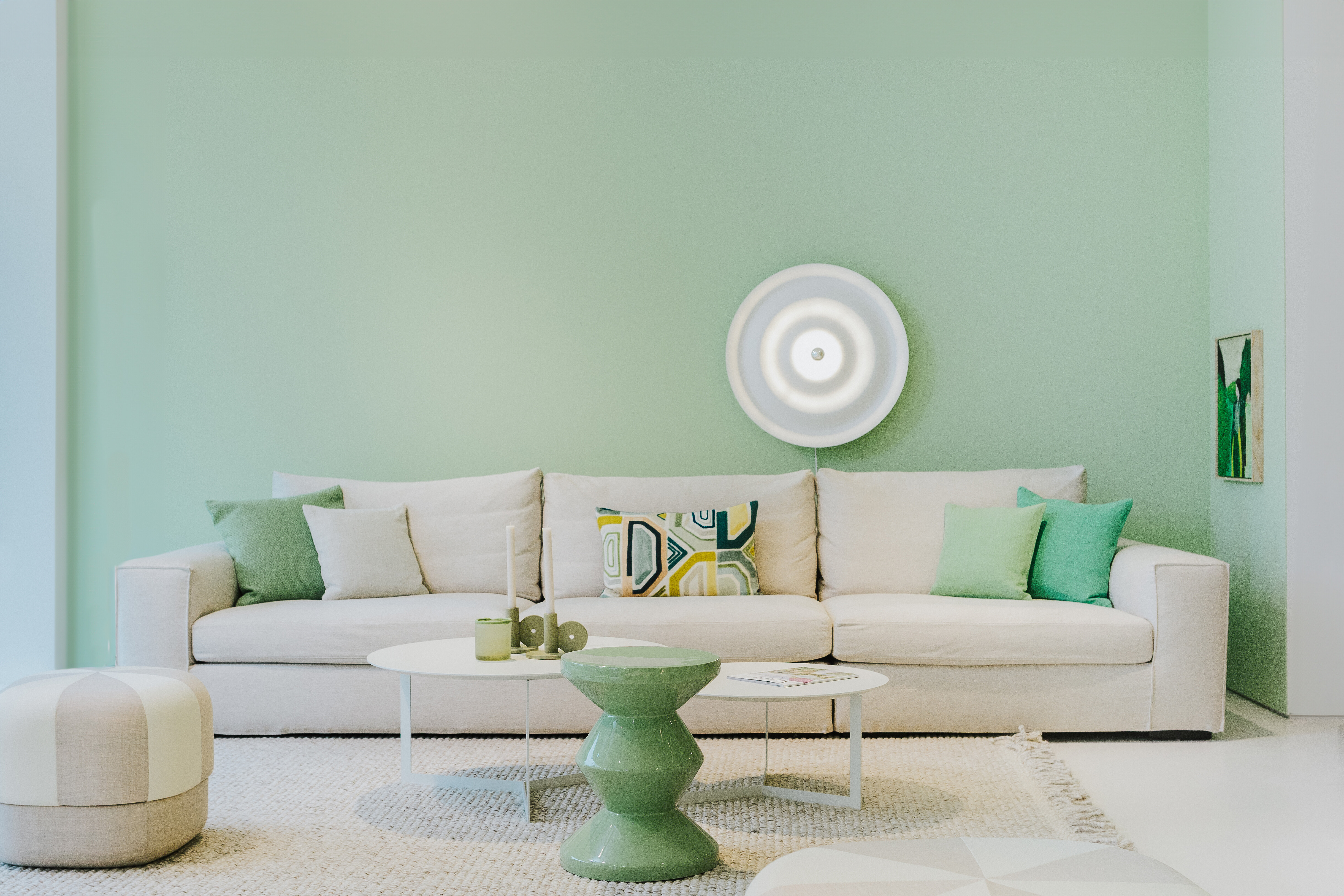 Wandleuchte w171 Alma von Wästberg über einem Sofa vor mintgrüner Wand mit Accessoires