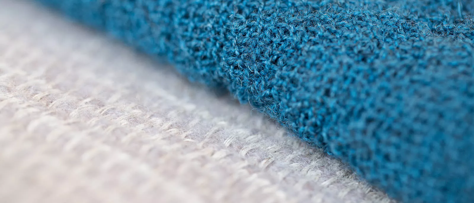 Detailaufnahme von zwei strukturierten Stoffoberflächen in Weiß und kräftigem Blau im Nahbereich