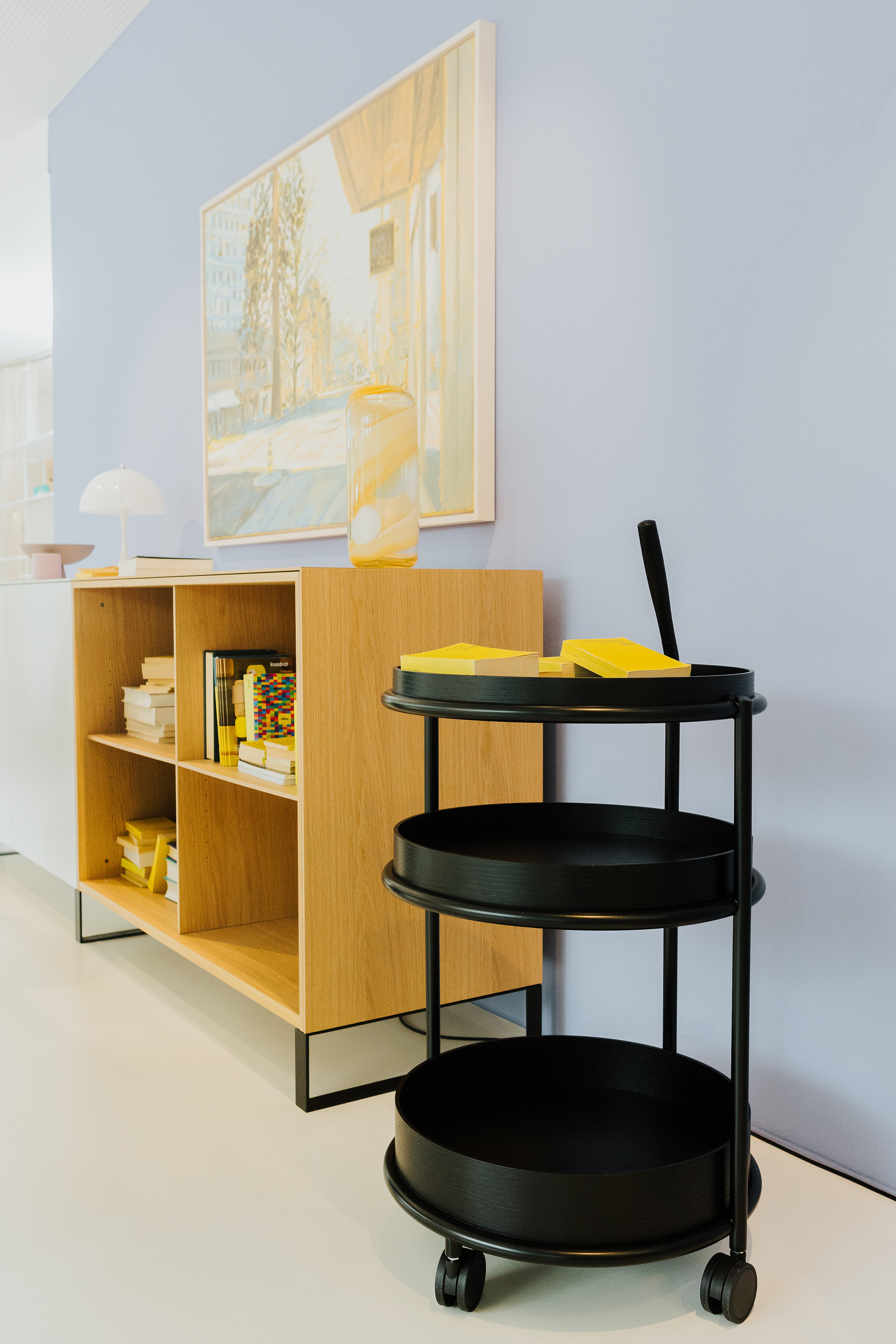 Offenes Sideboard aus Holz mit dekorativem Inhalt und runder Servierwagen in Schwarz