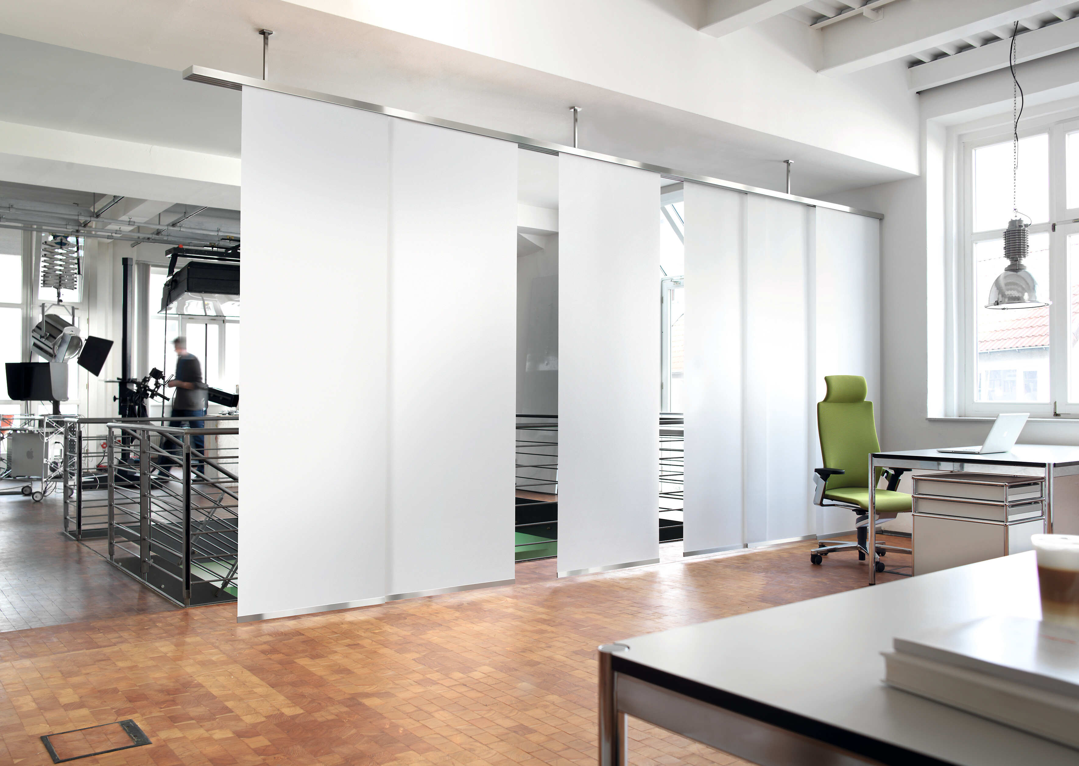Deckengeführte Flächenvorhänge als Raumteiler in einem lichtdurchfluteten Büro