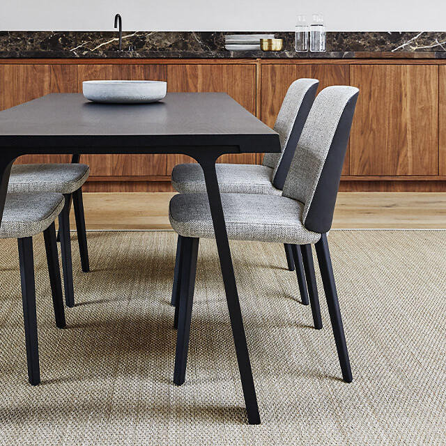 Esstisch aus Holz mit vier gepolsterten Stühlen auf hellem Teppich