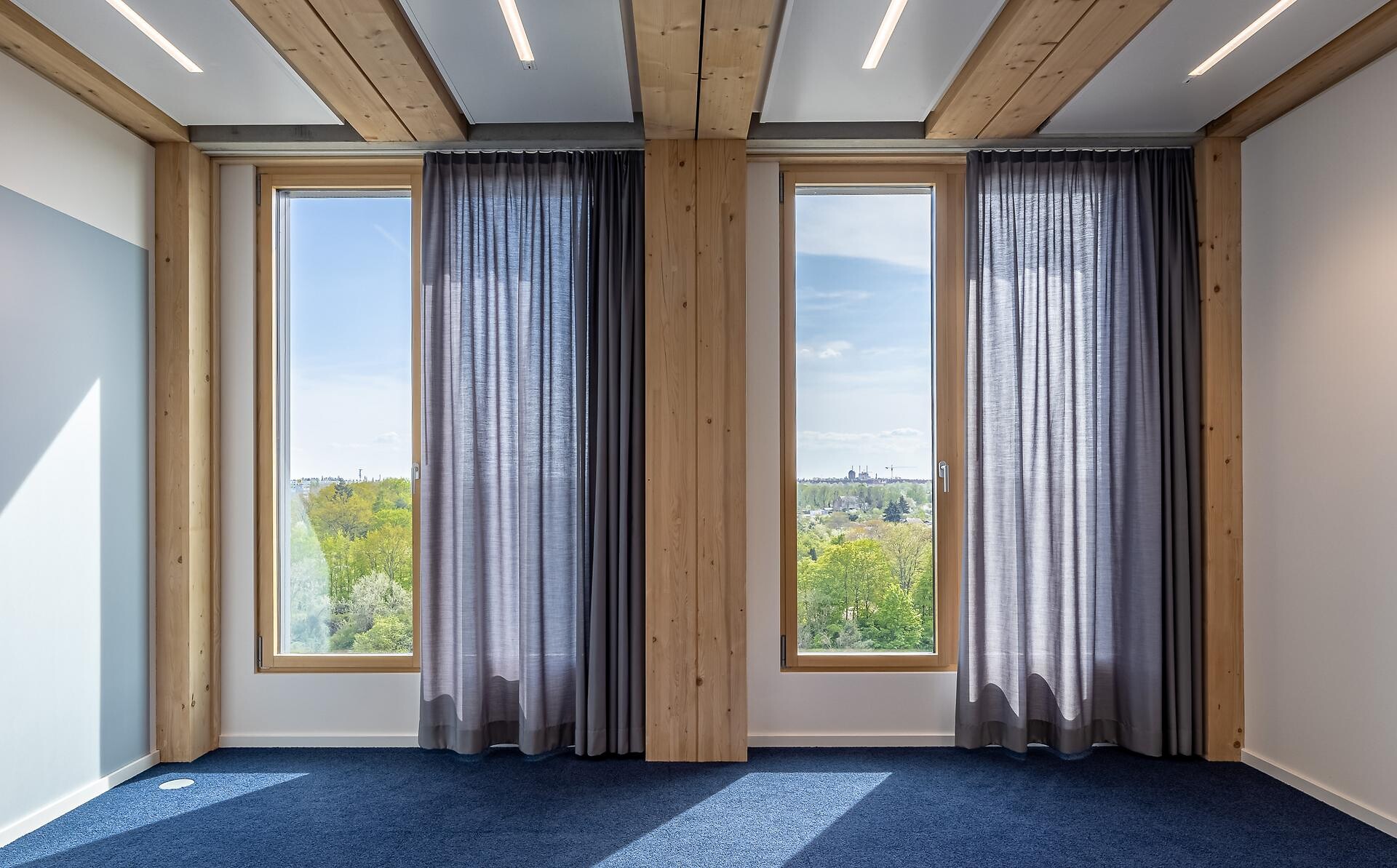 Fensterfront mit zwei bodenlangen, transparenten Vorhängen in Hellgrau